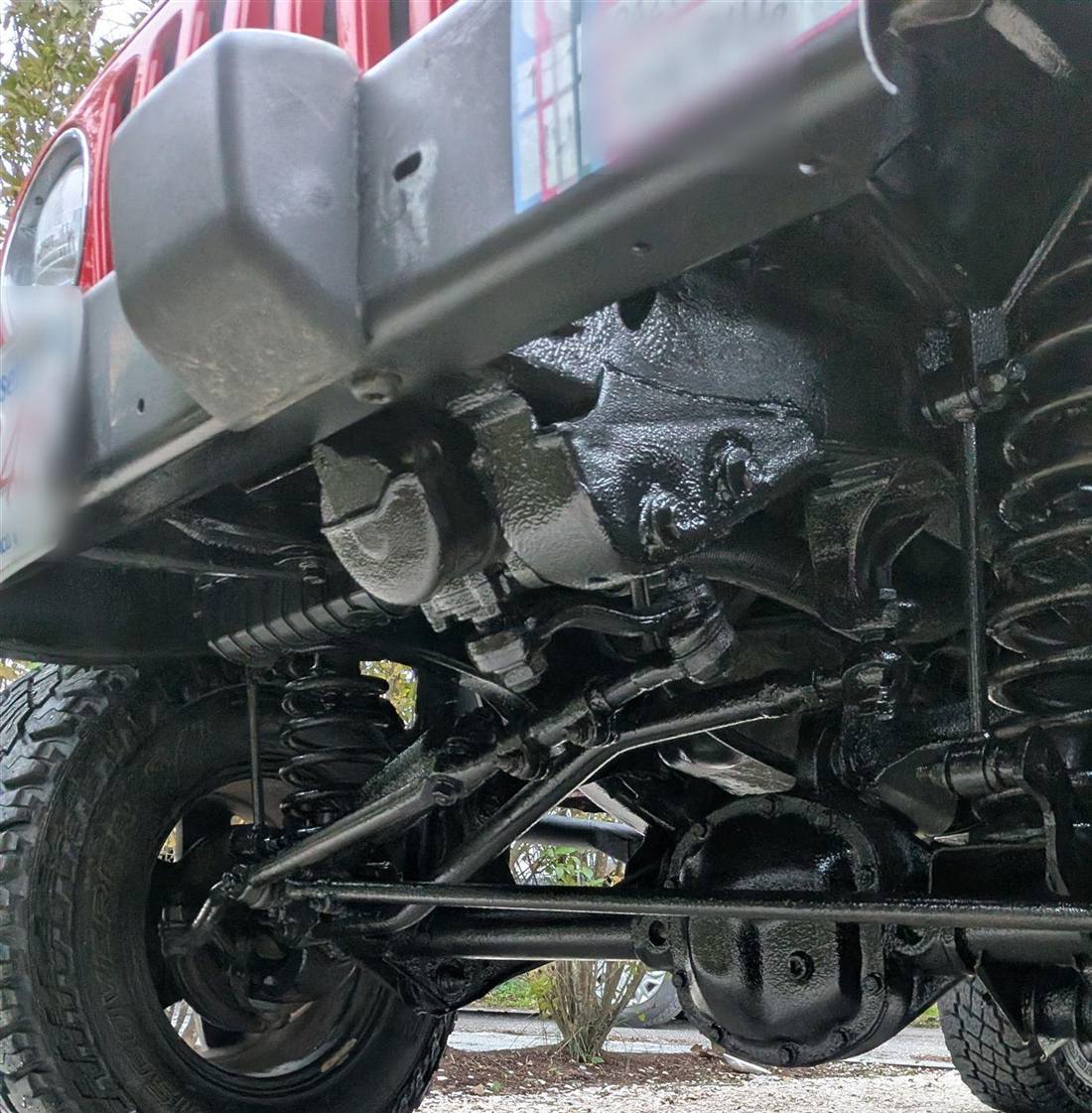 Fresh black undercoating across a Jeep chassis and axles